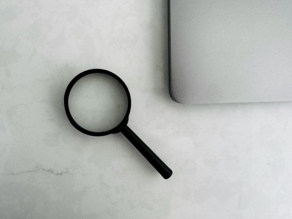 Magnifying glass beside a laptop representing careful backlink and link placement evaluation