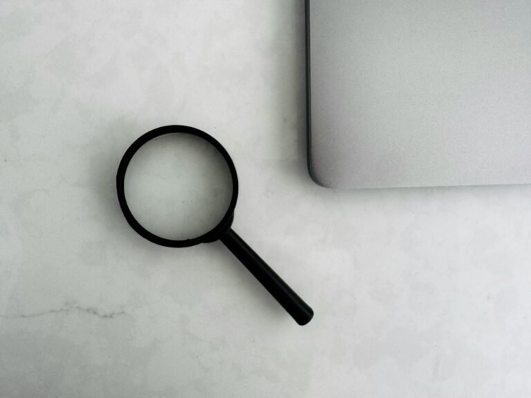 Magnifying glass beside a laptop representing careful backlink and link placement evaluation